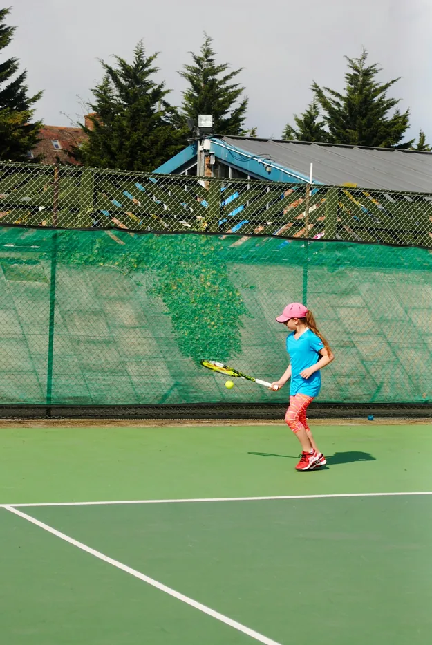 Youth tennis player hitting a ball on an outdoor court
